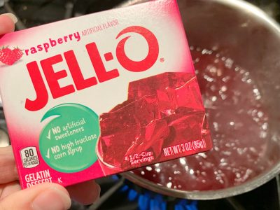 Adding raspberry gelatin to the juice mixture Adding raspberry gelatin to the juice mixture